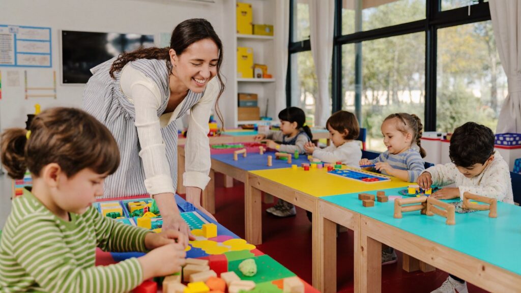 Anaokulu sınıfında öğretmeniyle ahşap bloklarla oynayan çocuklar